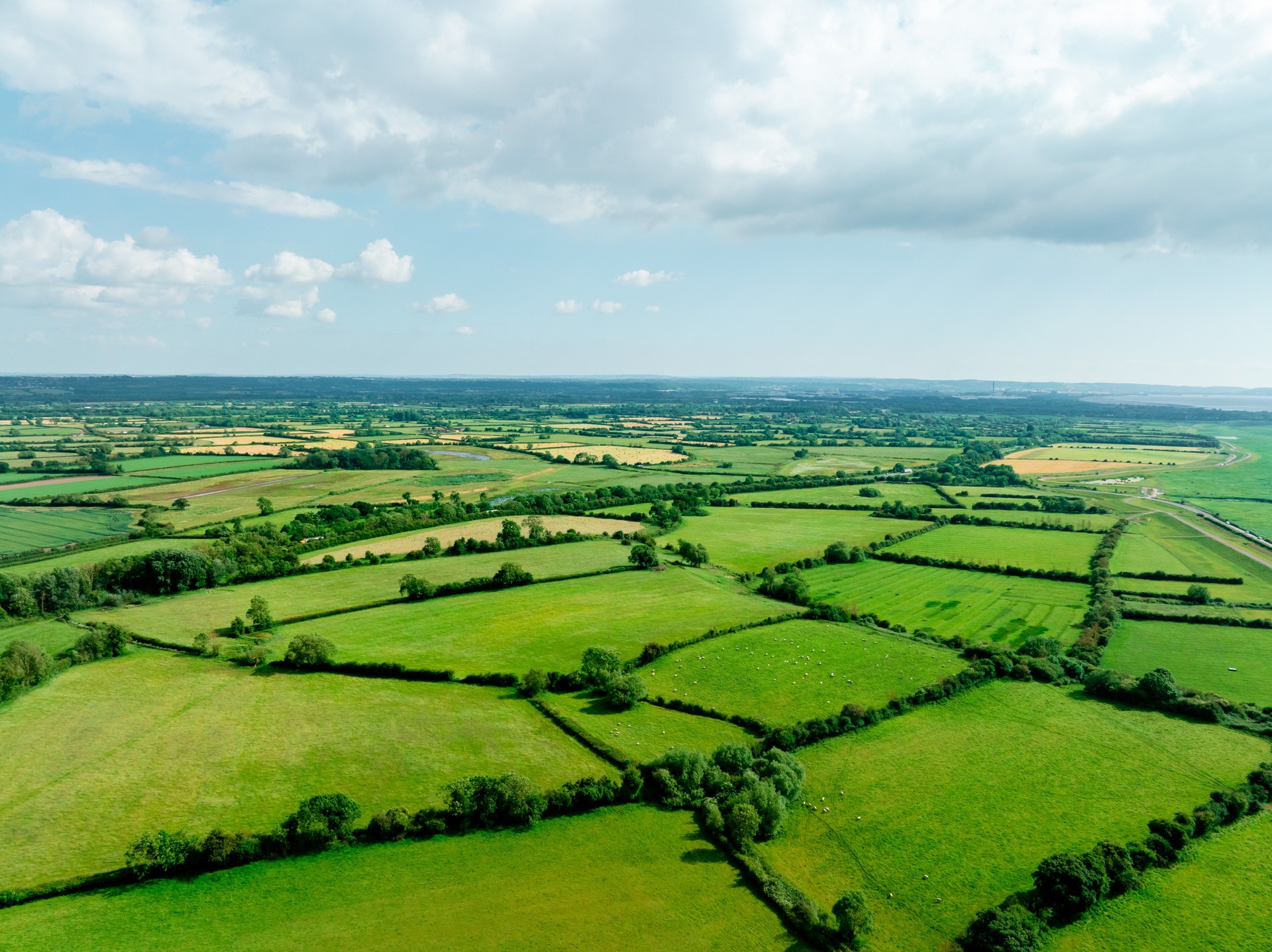 Aerial view of beautiful agricultural fields with cloudy blue sky in England
